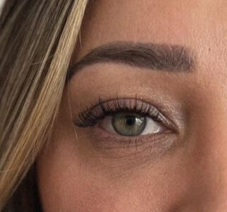 Wispy natural lash extensions on a client with green eyes