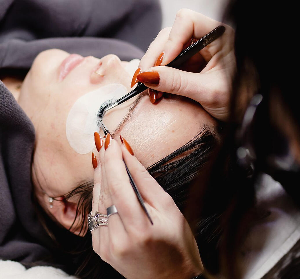 Close-up of lash extensions being applied with tweezers